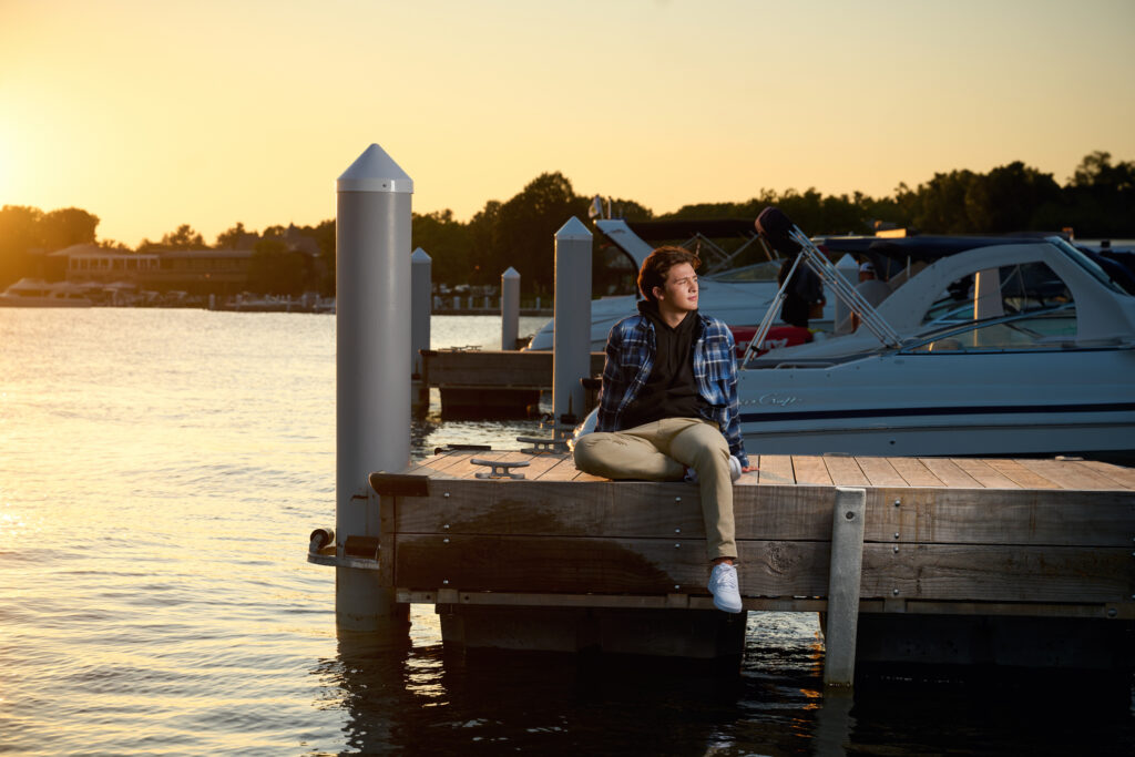 Senior Picture Photographer Captures Relaxed Portrait on Lakeside Dock at Sunset