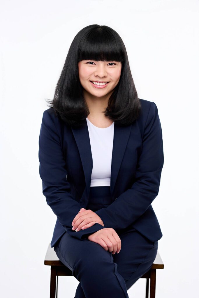 Corporate headshot session featuring professional woman in navy blazer with clean gray studio background