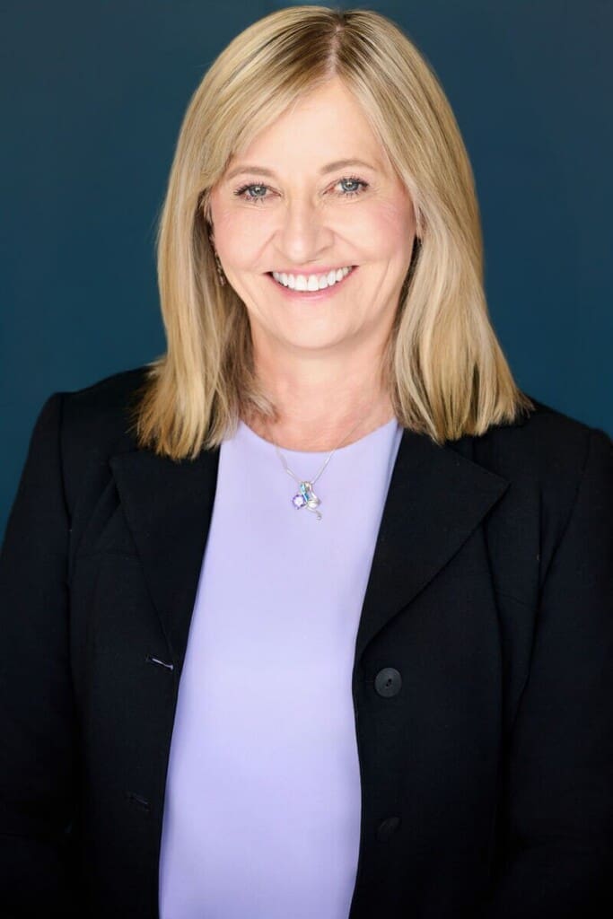 Bold professional headshot of woman in black blazer and lavender shirt against teal background St. Paul Megan Engeseth Photography